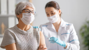 Doctor giving a senior woman a vaccination.