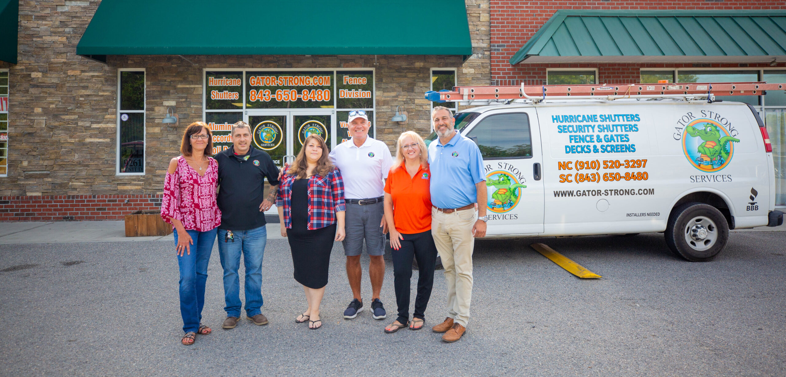 picture of staff of gator strong standing outside of their building in front of the gator strong van