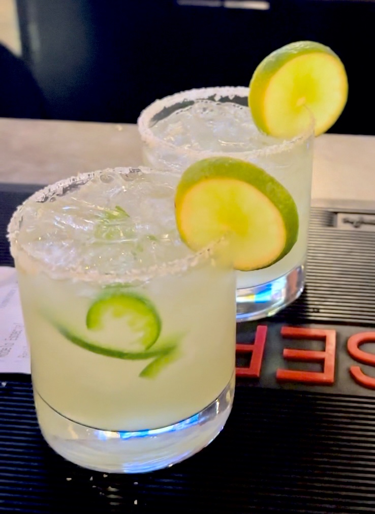 A refreshing scene at Pies & Pints in Fayetteville, WV, featuring a round of margaritas on the rocks, served in salt-rimmed glasses with lime wedges, embodying a perfect blend of tart and sweet
