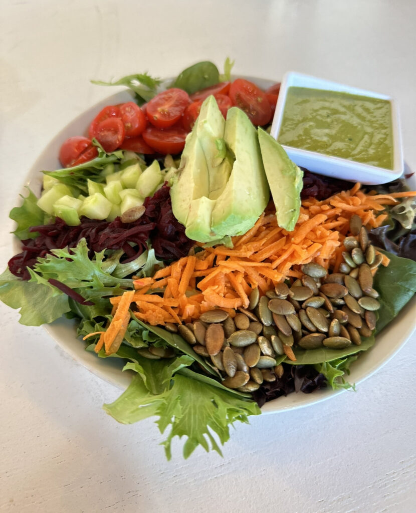 Earth Salad topped with mixed organic greens, carrots, avocado, tomatoes, sunflower seeds, cucumber and their original earth cafe dressing