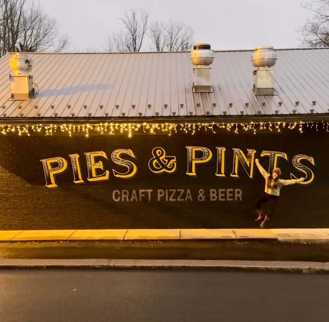 The exterior of Pies & Pints in Fayetteville, WV, showcases a charming, rustic facade with a welcoming sign, outdoor seating, and a lively, inviting atmosphere