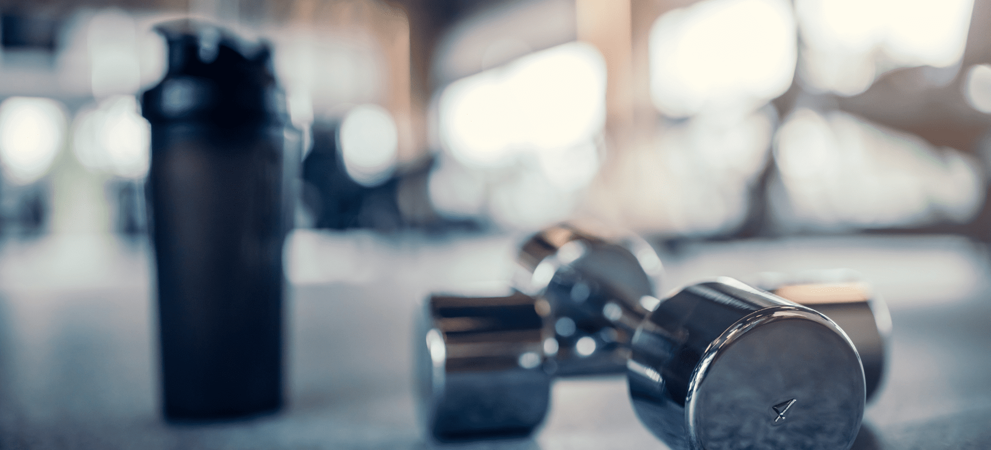 dumbells in a gym and a water tumbler