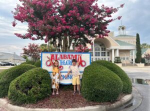 Two children hold hands in front of the sign for the Alabama Theater in North Myrtle Beach, SC.