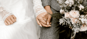 couple holding hands at their wedding, the man is holding the bridal bouquet