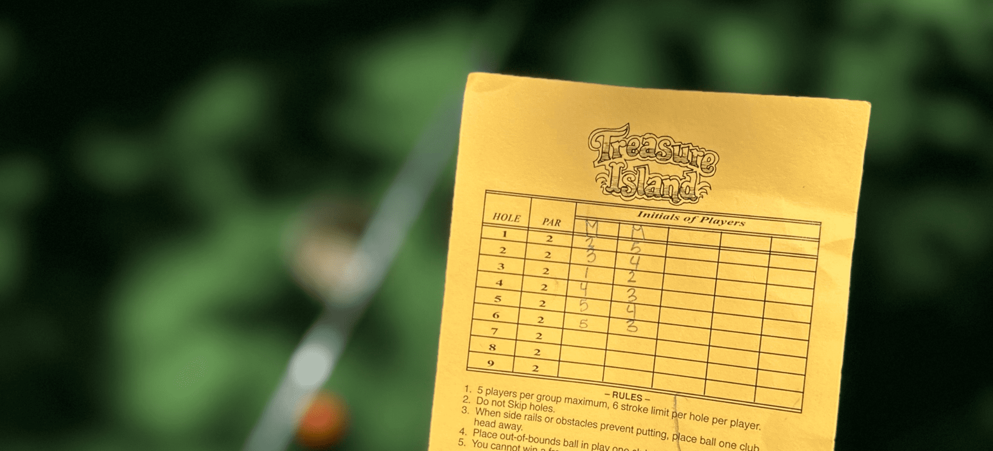 score card from treasure island mini golf with putter and ball in background