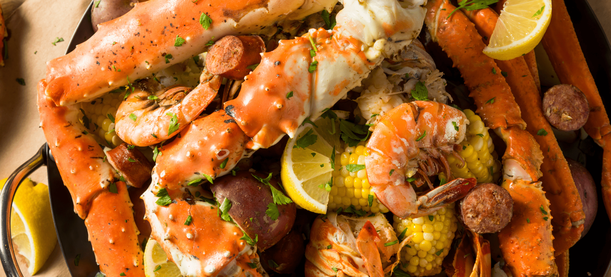 a dish of different types of seafood like crab, sausages, corn, potatoes