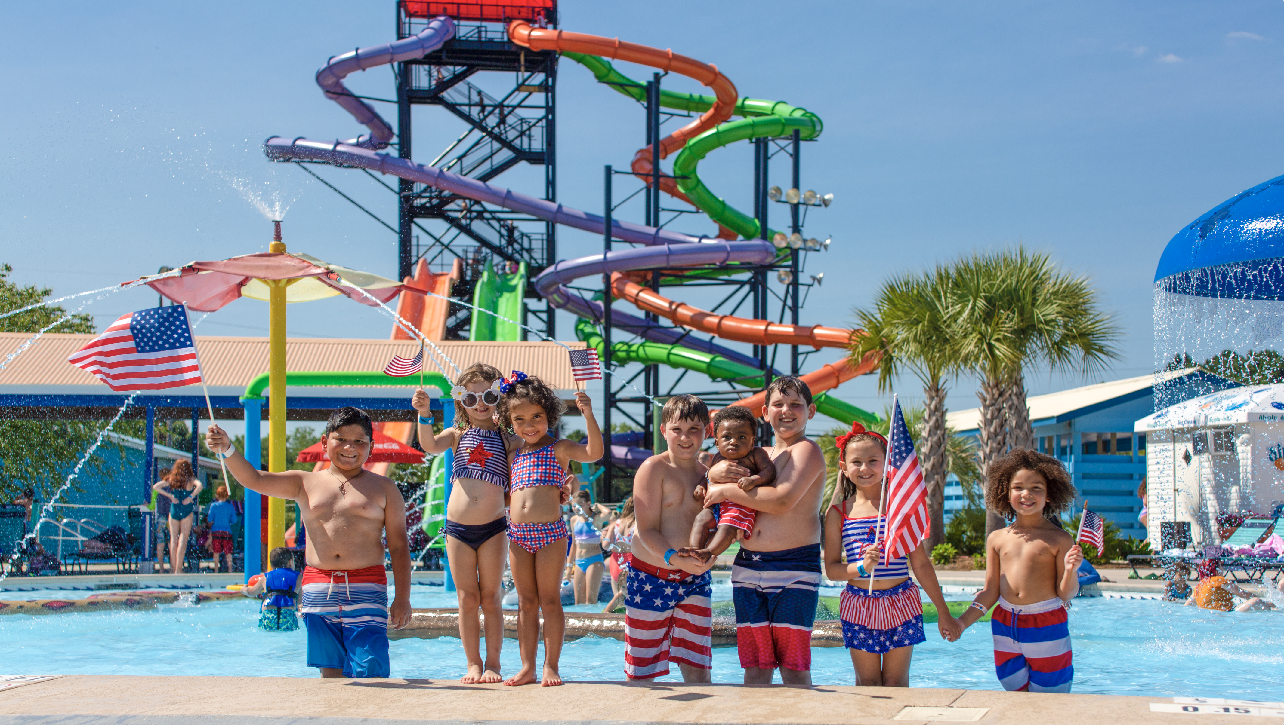a group of small children standing in front of tall waterslides at Myrtle Waves, a Myrtle Beach waterpark