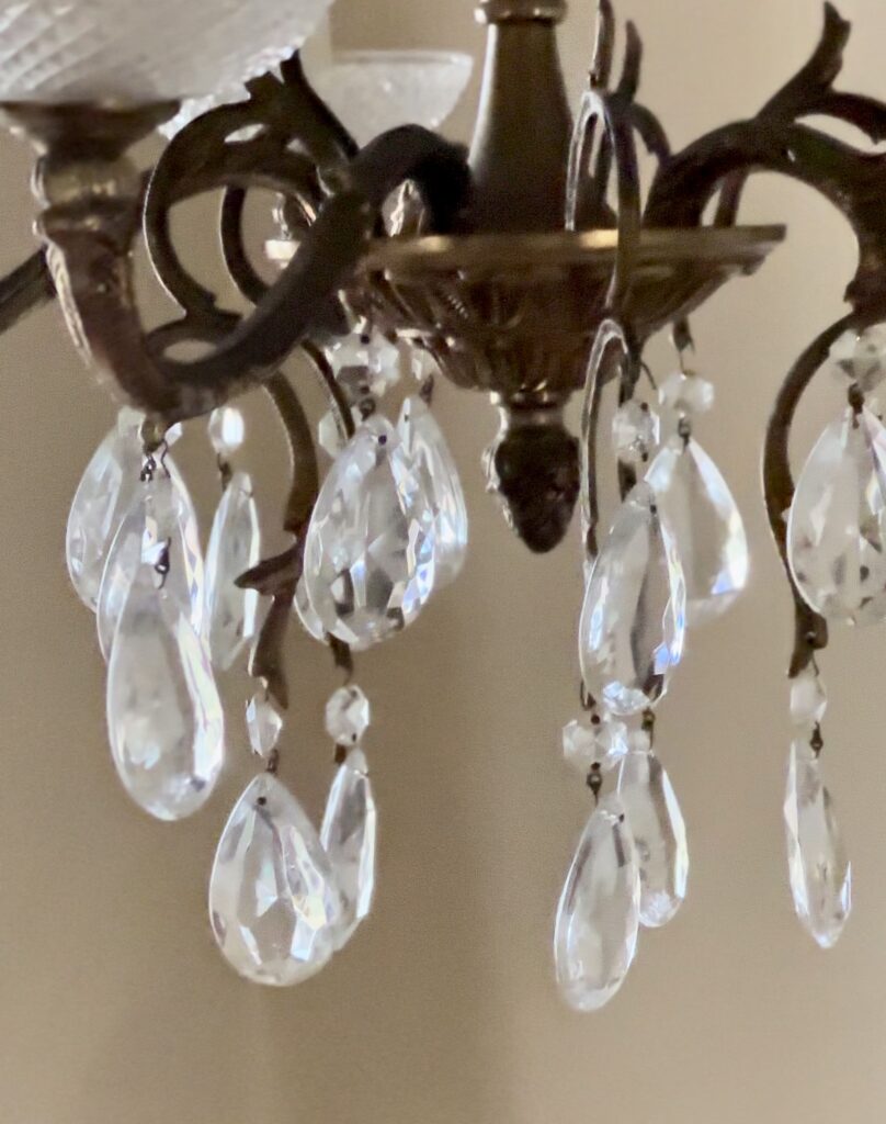 A photo of a 1930s vintage chandelier in a Greenbrier Avenue Airbnb, displaying intricate designs and elegant crystal hangings, casting a warm, ambient light in a charmingly decorated room