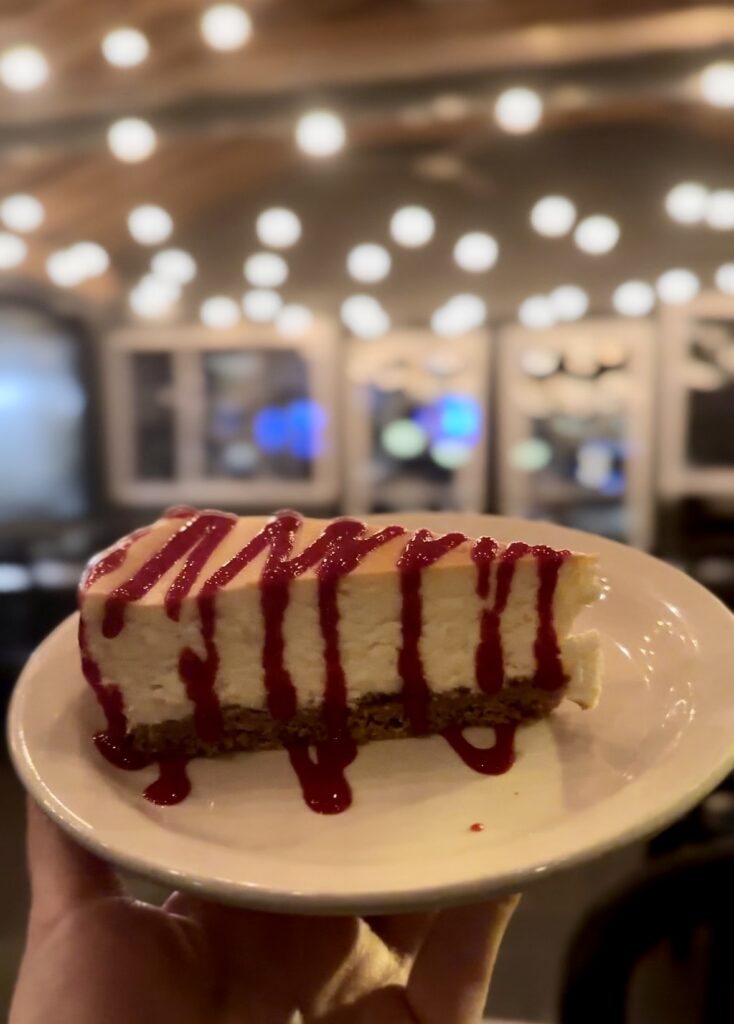At Pies & Pints in Fayetteville, WV, a delectable strawberry-topped cheesecake dessert is presented, featuring a golden, crumbly crust and a luscious layer of fresh, juicy strawberries on top.