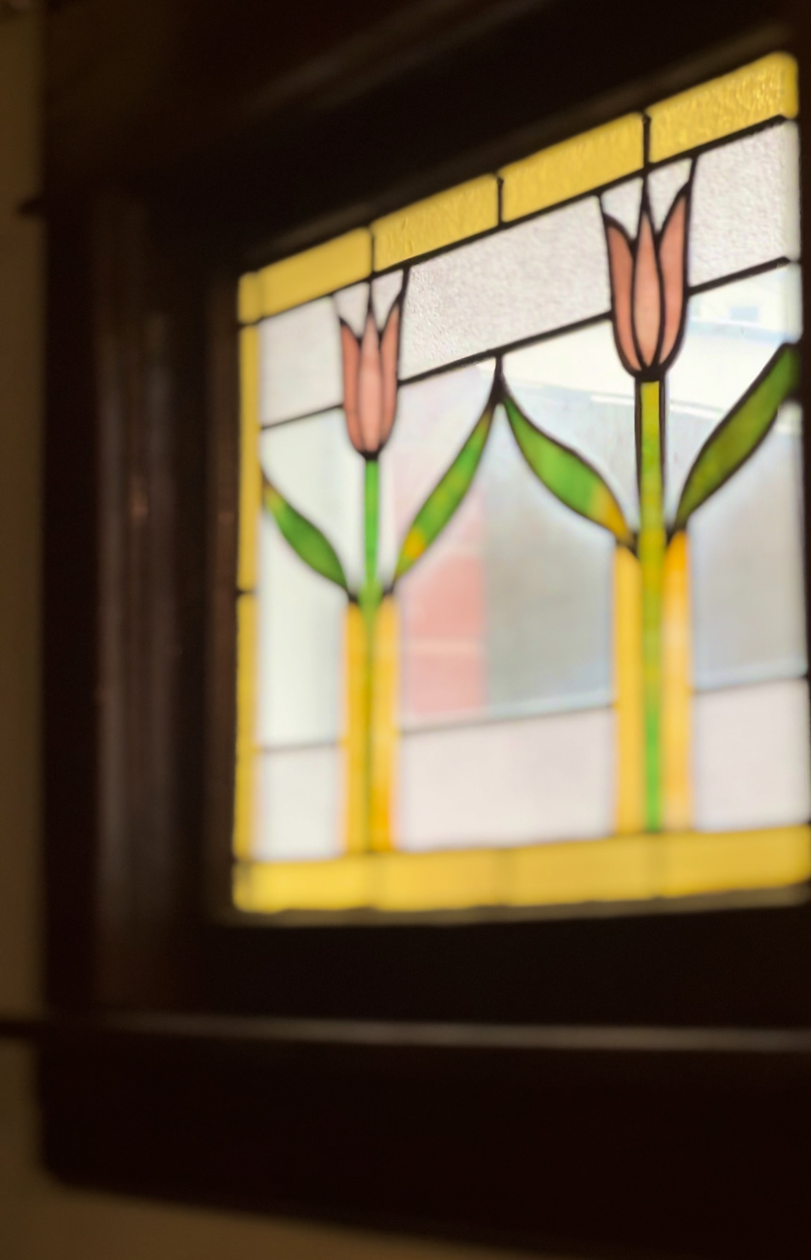 Elegant stained glass flower window decor graces the 1930s Airbnb living room with vibrant colors and timeless beauty.